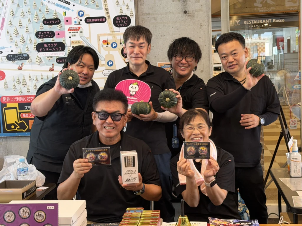 信州タッチミーティングin佐久で、北斗の拳グッズやかぼちゃを手に笑顔のタク技研スタッフ一同